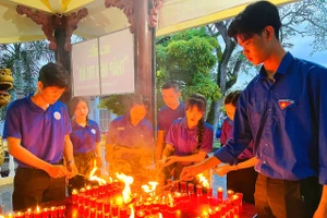 Trọng Văn (bên trái) tham gia thắp nến tri ân tại đền thờ liệt sĩ Thị trấn Mỏ Cày (Bến Tre). Ảnh: NVCC