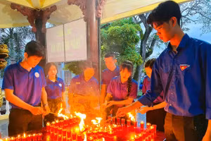 Trọng Văn (bên trái) tham gia thắp nến tri ân tại đền thờ liệt sĩ Thị trấn Mỏ Cày (Bến Tre). Ảnh: NVCC