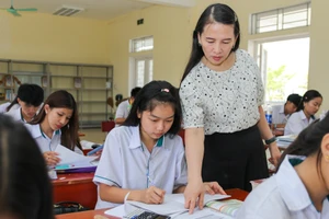 Giáo viên hướng dẫn các em lưu học sinh Lào làm bài tập.