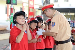 Học sinh được Cảnh sát giao thông hướng dẫn sử dụng mũ bảo hiểm.
