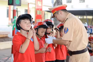 Học sinh được Cảnh sát giao thông hướng dẫn sử dụng mũ bảo hiểm.