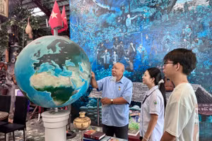 Cựu chiến binh Lâm Xuân Quang cùng học sinh tham quan quả địa cầu, tái hiện hành trình ra đi tìm đường cứu nước của Bác Hồ. Ảnh: Thùy Linh