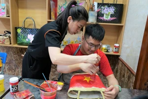 Cô giáo hướng dẫn trẻ vẽ tranh lên túi cói. Ảnh: Hồ Lài
