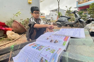 Ngô Tấn Phú - học sinh lớp 5B, Trường Tiểu học số 1 Nhơn Bình (phường Quy Nhơn Đông, tỉnh Gia Lai) phơi những cuốn vở ướt sũng nước. Ảnh: Dung Nguyễn