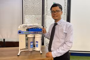 TS Đỗ Hữu Quyết bên hệ thống lọc nước do mình chế tạo. Ảnh: Hà An