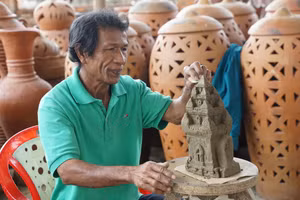 Nghệ nhân làng gốm Bàu Trúc bên tác phẩm tháp Chăm chưa hoàn thiện.