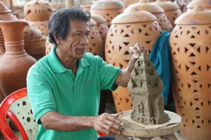 Nghệ nhân làng gốm Bàu Trúc bên tác phẩm tháp Chăm chưa hoàn thiện.