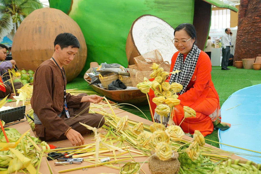 Bà Nguyễn Thị Quyên Thanh, Phó Chủ tịch UBND tỉnh Vĩnh Long theo dõi nghệ nhân trình diễn đan lá dừa. (Ảnh: TTVH Vĩnh Long) ba-ntqt.jpg