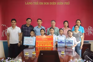 Đại diện Công ty Cổ phần Sách và Thiết bị trường học Điện Biên và Sở GD&ĐT Điện Biên trao quà cho các em nhỏ Làng trẻ em SOS Điện Biên Phủ.