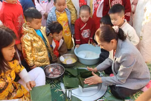 Cô giáo trường Mầm non Thanh Bình hướng dẫn, hỗ trợ các em gói bánh chưng.