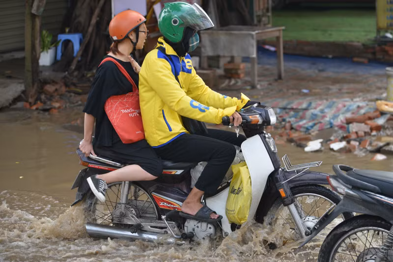 Người dân Hà Nội co chân trên xe máy lội qua đường ngập dù trời không mưa