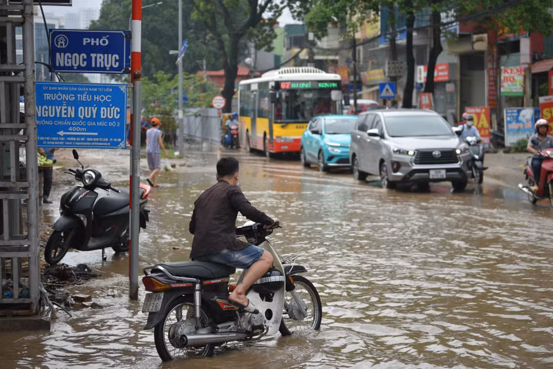Người dân Hà Nội co chân trên xe máy lội qua đường ngập dù trời không mưa