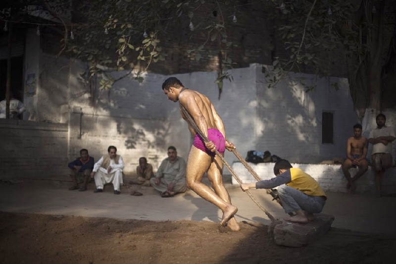 Một pehlwan đang kéo tấm gỗ nhằm chuẩn bị sàn bùn cho một trận thi đấu ở sàn vật Bamma, sàn vật lớn nhất ở Lahore (Pakistan). Đá cuội được cào khỏi sàn vật trước khi diễn ra trận đấu Một pehlwan đang kéo tấm gỗ nhằm chuẩn bị sàn bùn cho một trận thi đấu ở sàn vật Bamma, sàn vật lớn nhất ở Lahore (Pakistan). Đá cuội được cào khỏi sàn vật trước khi diễn ra trận đấu