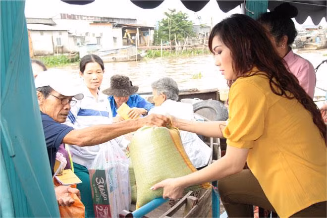 Kavie Trần (bìa phải) trao quà cho bà con nghèo miền sông nước Cần Thơ