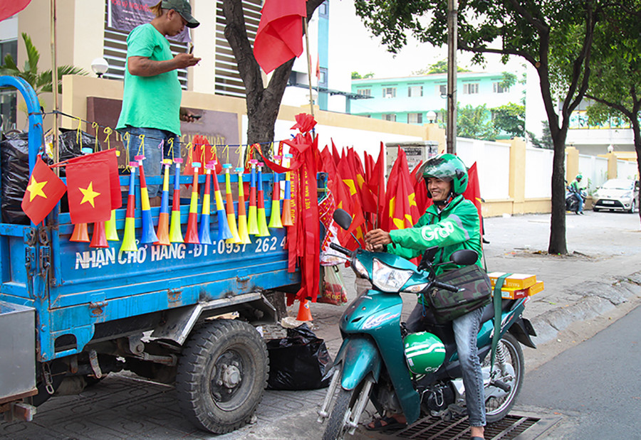 Tài xế xe ôm công nghệ tranh thủ thời gian nghỉ, mua những lá cờ nhỏ, treo trước xe cổ vũ cho tuyển U22 trên đường Bạch Đằng (Q. Bình Thạnh, TP.HCM)