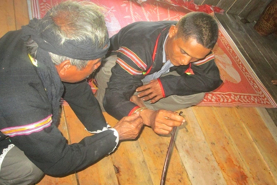 Thầy cúng đeo vòng đồng vào tay người được cúng