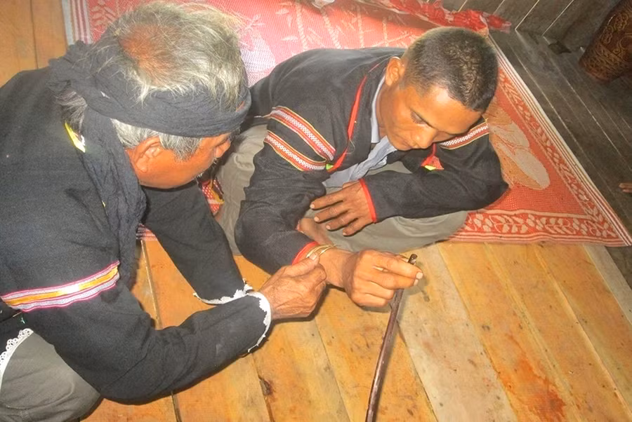 Thầy cúng đeo vòng đồng vào tay người được cúng