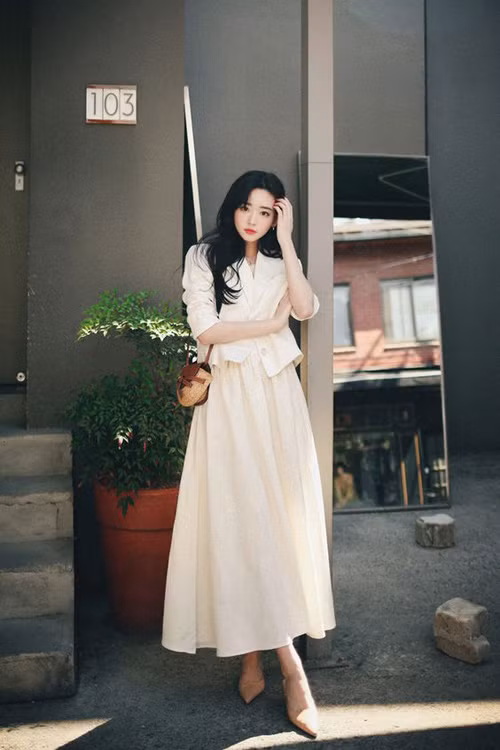 Váy liền thân màu trắng ngà kết hợp cùng áo blazer dáng lửng, túi cói và giày nude mang tới set đồ thanh lịch cho chị em công sở.