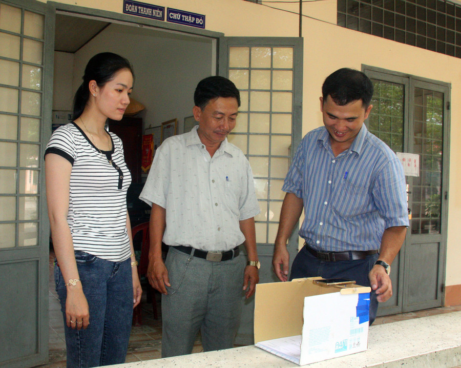 Thầy Cường (phải) hướng dẫn các giáo viên chấm thi trắc nghiệm bằng điện thoại