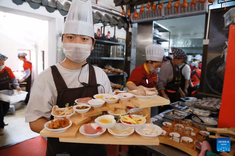 Nhân viên chuẩn bị món ăn cho khách tại quán bún gạo ở Mông Tự, tỉnh Vân Nam. am-thuc-truyen-thong-va-xu-huong-moi-bung-no-trong-dip-tet-o-trung-quoc-5.jpg