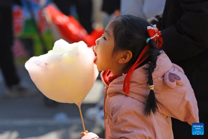 Bé gái ăn kẹo bông tại công viên ở Đằng Châu, tỉnh Sơn Đông. am-thuc-truyen-thong-va-xu-huong-moi-bung-no-trong-dip-tet-o-trung-quoc-18.jpg