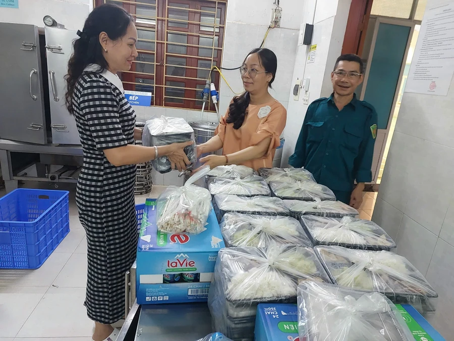 Cô Phạm Thị Ngà - Hiệu trưởng Trường Tiểu học Nguyễn Đức Cảnh giao cơm cho cán bộ phường An Dương để phục vụ người dân tạm lãnh sau bão.