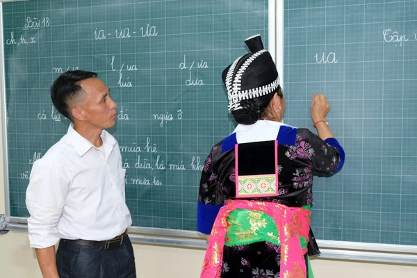 Thầy giáo Lỳ Bá Của (giáo viên Trường Phổ thông DTBT Tiểu học Hữu Khuông, Nghệ An) dạy học xóa mù chữ cho người dân. Ảnh: Hồ Lài