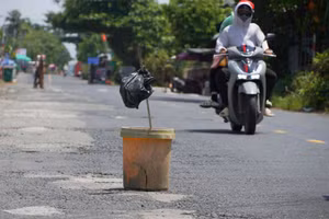 Người dân tự dặm vá đường và đặt những vật dụng cảnh báo tạm thời. (Ảnh: Yến Phương)