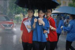 Tình nguyện viên hỗ trợ thí sinh rời điểm thi khi mưa lớn.