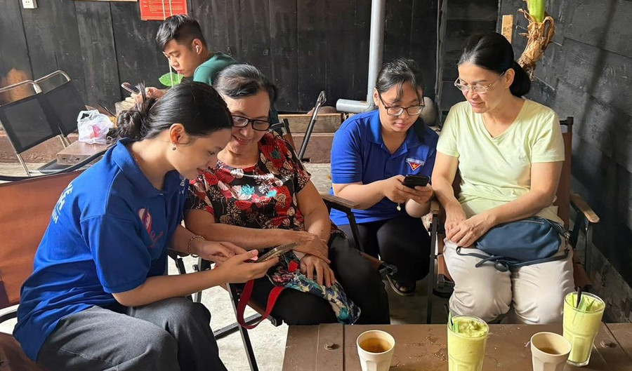 Tình nguyện viên hỗ trợ người dân cài đặt các ứng dụng chuyển đổi số trong đời sống hằng ngày. Ảnh: Mặt trận phường Bình Thạnh. 