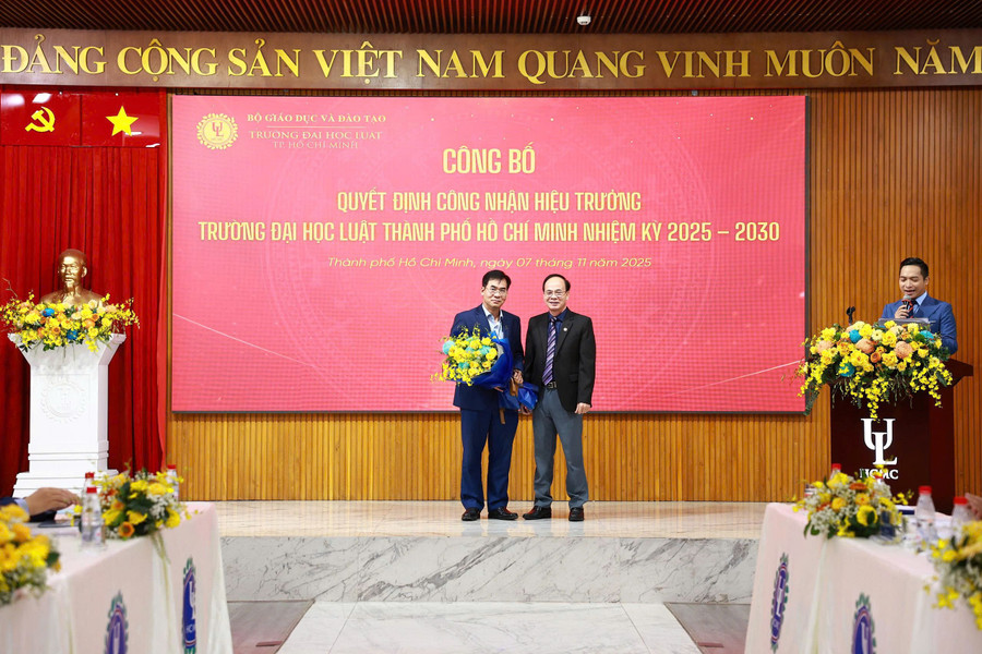 PGS.TS Vũ Văn Nhiêm - Chủ tịch Hội đồng trường (phải) tặng hoa cho TS Lê Trường Sơn - Hiệu trưởng Trường Đại học Luật TPHCM. Ảnh: HCMULAW. 