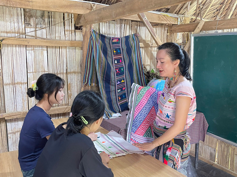 Nghệ nhân Châu Mạ hướng dẫn sinh viên tìm hiểu chi tiết thổ cẩm dân tộc Châu Mạ. Ảnh: NVCC. 