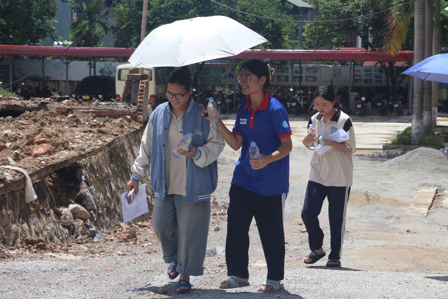Tình nguyện viên tiếp nước, che nắng cho thí sinh bước vào môn thi toán. Tình nguyện viên tiếp nước, che nắng cho thí sinh bước vào môn thi toán.