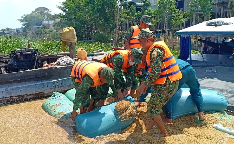 Cán bộ, chiến sĩ Đồn Biên phòng Phú Hội trục vớt phương tiện, số lúa bị chìm trên sông.