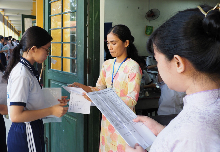 Cán bộ coi thi đọc tên thí sinh vào phòng thi tại điểm thi Trường THPT Trưng Vương.