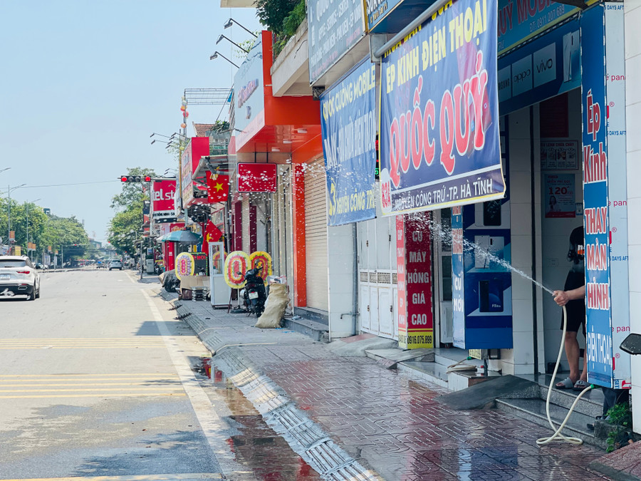 Những hộ dân sống tại đường Nguyễn Công Trứ dùng vòi xịt nước làm dịu bớt hơi nóng phả lên từ mặt đường nhựa.