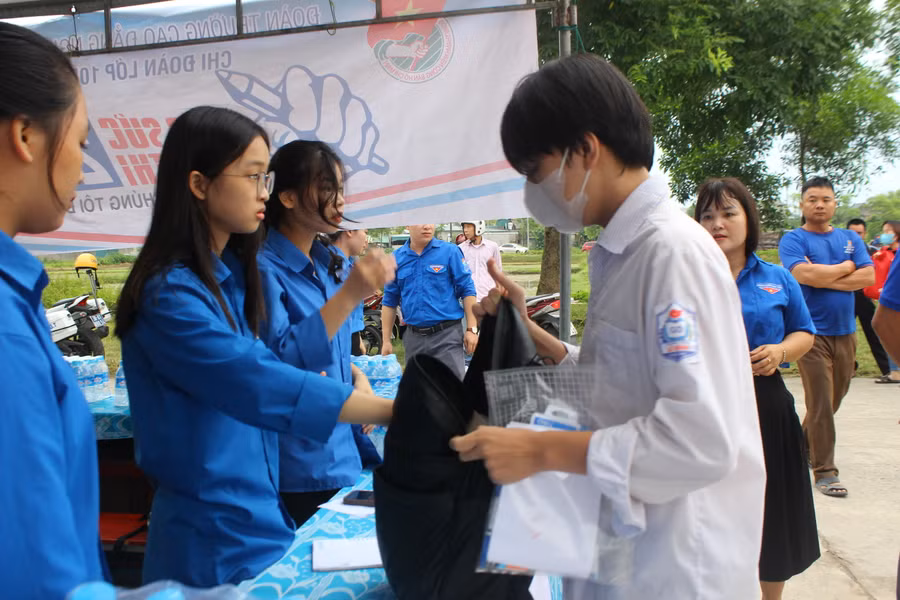 Tình nguyện viên giữ đồ giúp thí sinh trước cổng trường.