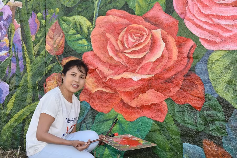 Họa sĩ Nguyễn Thu Thủy vẽ loài hoa mang biểu tượng tình yêu trên bức tường đê bên sông Seine.