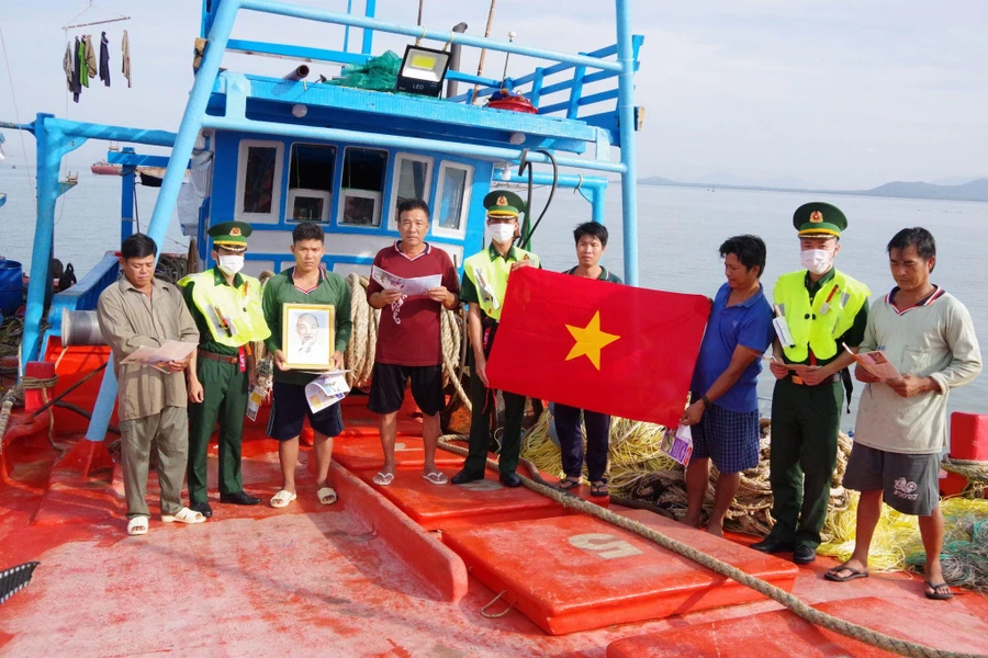 Cán bộ Biên đội III/22, Hải đoàn Biên phòng 18 trao tặng cờ Tổ quốc, phát tờ rơi tuyên truyền cho ngư dân.