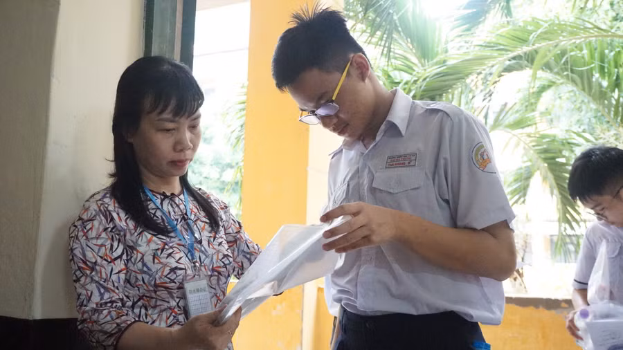 Cán bộ coi thi đọc tên thí sinh vào phòng thi tại điểm thi Trường THPT Trưng Vương.