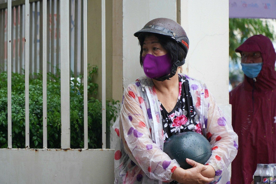 Phụ huynh "đội mưa" ngóng con con làm thủ tục dự thi.