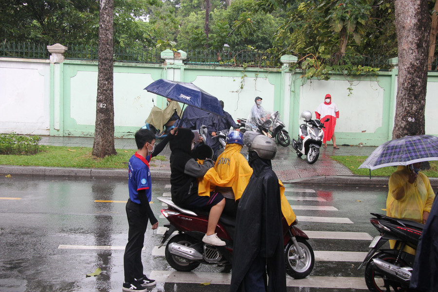 Các sinh viên tình nguyện che ô cho thí sinh ra khu vực phụ huynh đợi khi hoàn thành buổi sinh hoạt quy chế.