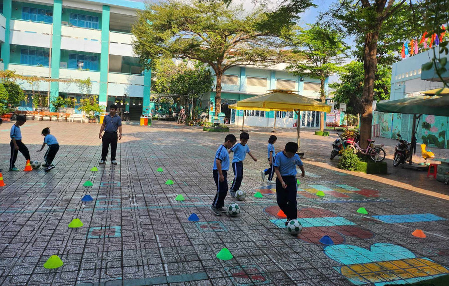 Giờ học thể dục của học sinh Trường tiểu học Lê Văn Thọ được tổ chức vào buổi sáng, dưới bóng cây và có bố trí quạt xung quanh.