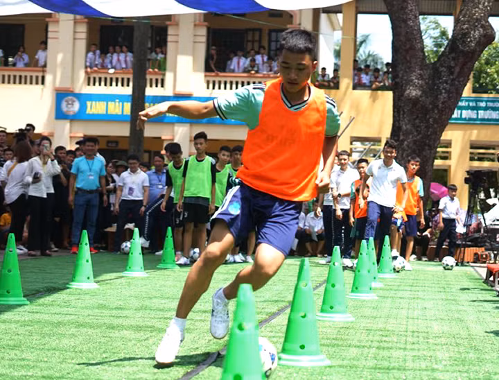 Một em học sinh trường THCS Phù Đổng thể hiện khả năng dẫn bóng cùng các cầu thủ Hà Nội T&T.