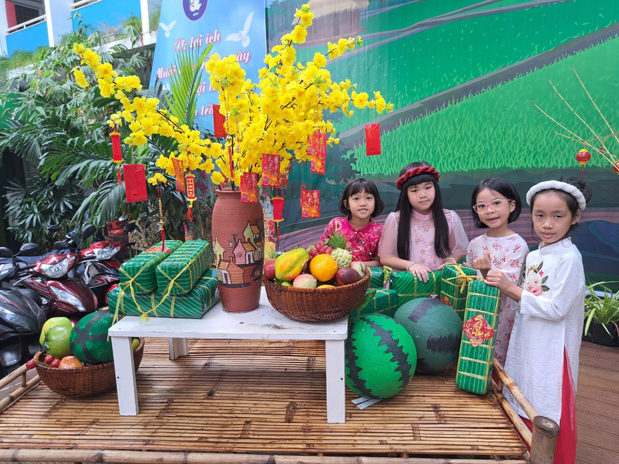 Các em học sinh tiểu học háo hức vui chơi trong tiểu cảnh Tết quê tại trường.