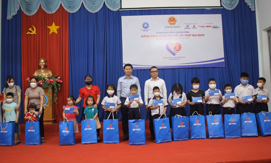 Ông Nguyễn Thanh Đề và ông Nguyễn Đắc Lực trao học bổng cho các em học sinh.