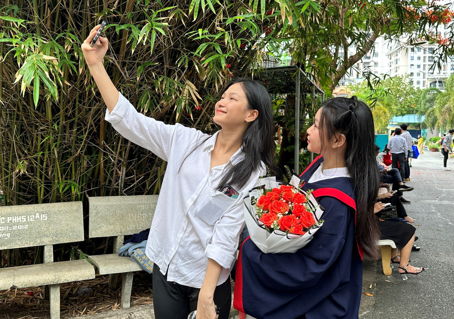 Thanh Mai (học sinh cầm hoa) lớp 12A12 cùng em gái lưu lại khoảnh khắc tại buổi lễ tri ân và trưởng thành.