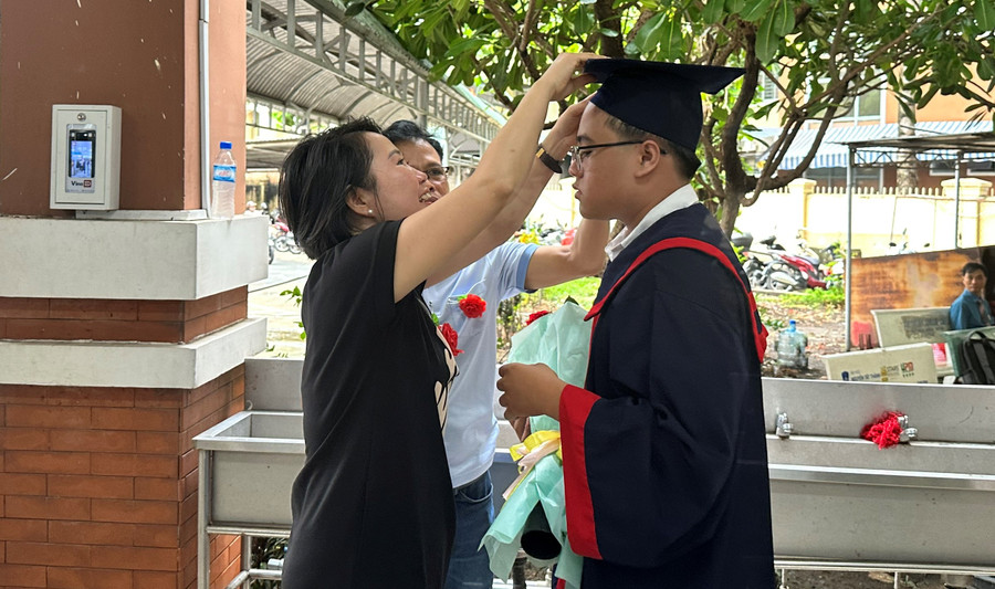 Phụ huynh chỉnh trang lại lễ phục tốt nghiệp cho con trai.