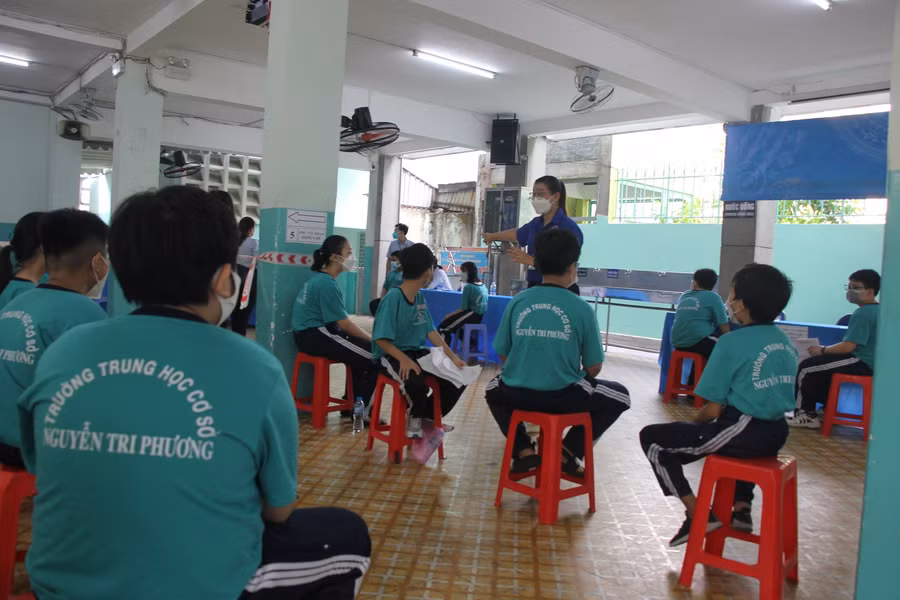 Các bạn tình nguyện viên hướng dẫn học sinh đến khu vực tiêm chủng tại điểm tiêm trường THCS Nguyễn Tri Phương.