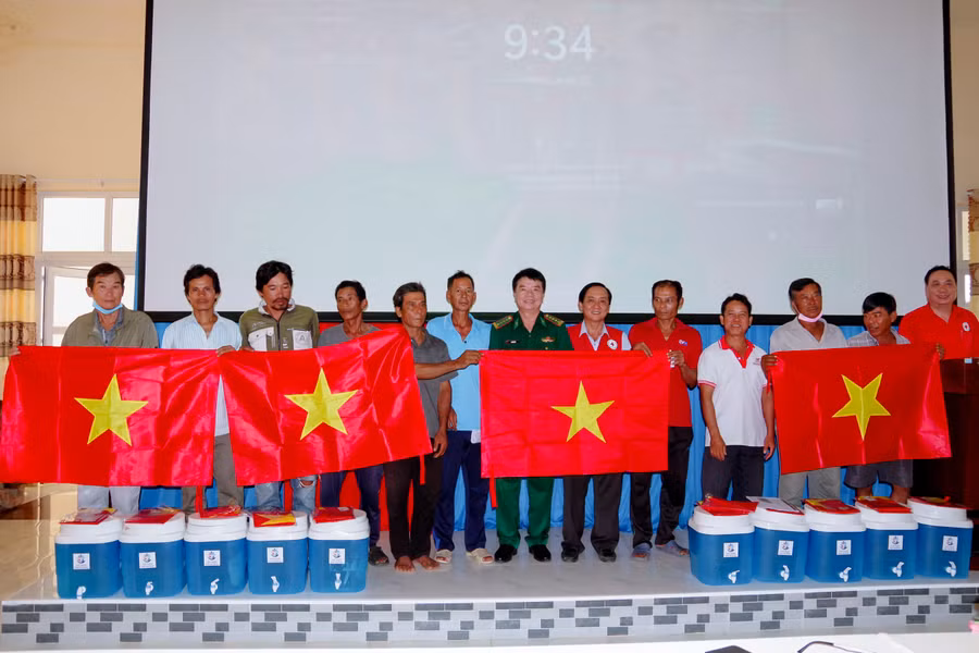 Ban tổ chức trao tặng cờ Tổ quốc và bình lọc nước cho ngư dân. (Ảnh: Hoàng Đoán)